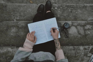 Person writing a brain dump list in a journal during a slow morning routine for productive days.
