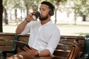 A student sitting on a park bench listening to an AI-generated study podcast on their tablet.