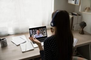 "A young professional wearing headphones and practicing her pitch with an AI interview coach on a laptop